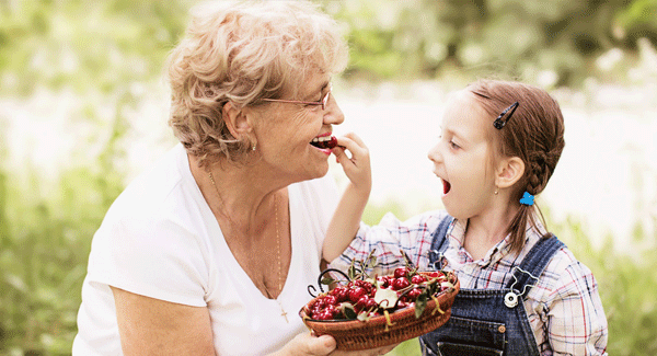 Grandmother and grand daughter eating fruit.